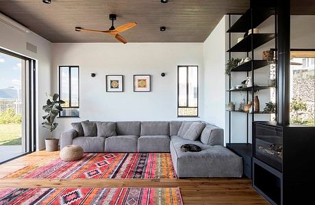 Cozy living room with L-shaped gray sofa, colorful patterned rug, and modern shelving.