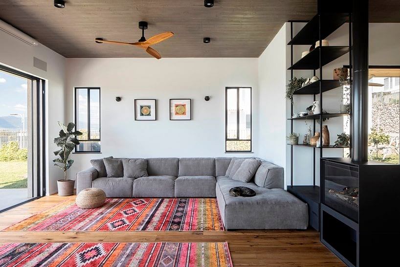 Cozy living room with L-shaped gray sofa, colorful patterned rug, and modern shelving.