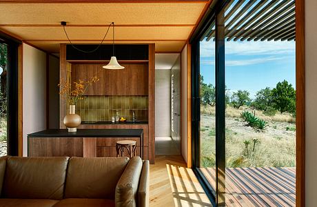 Warm, rustic interior with wooden finishes, open glass walls, and desert landscape view.