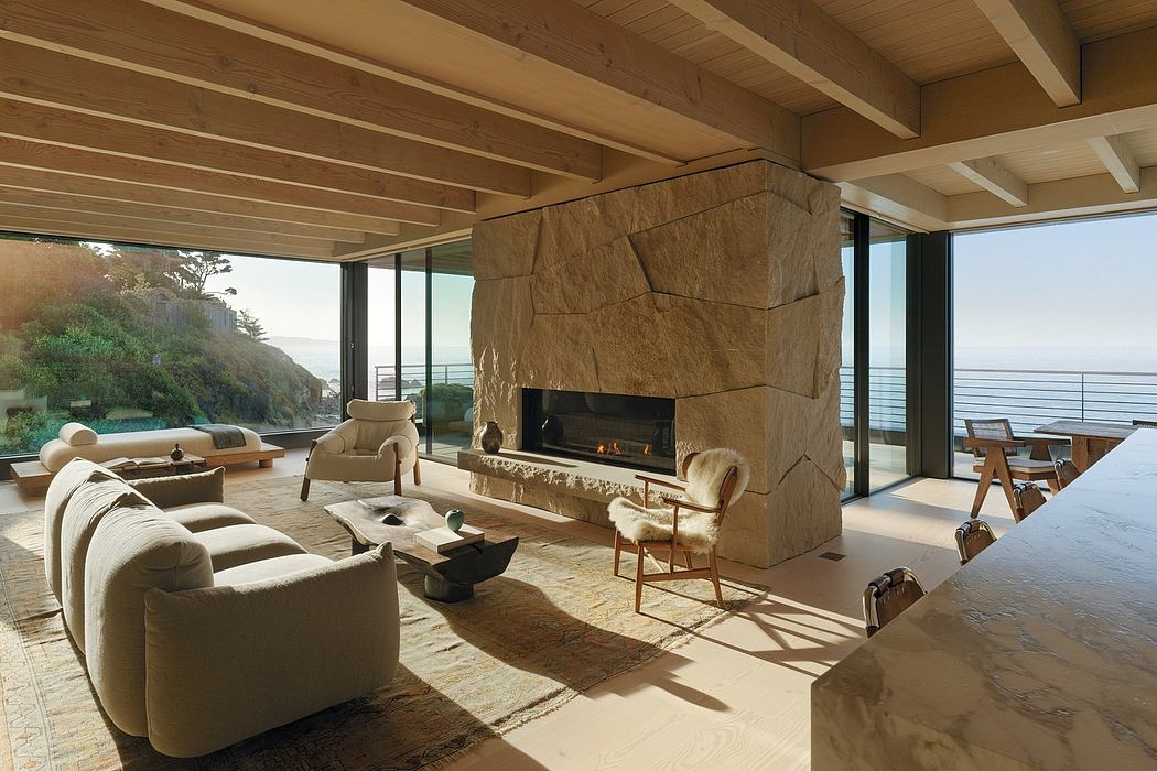 Cozy living space with wooden beams, large stone fireplace, and panoramic ocean views.