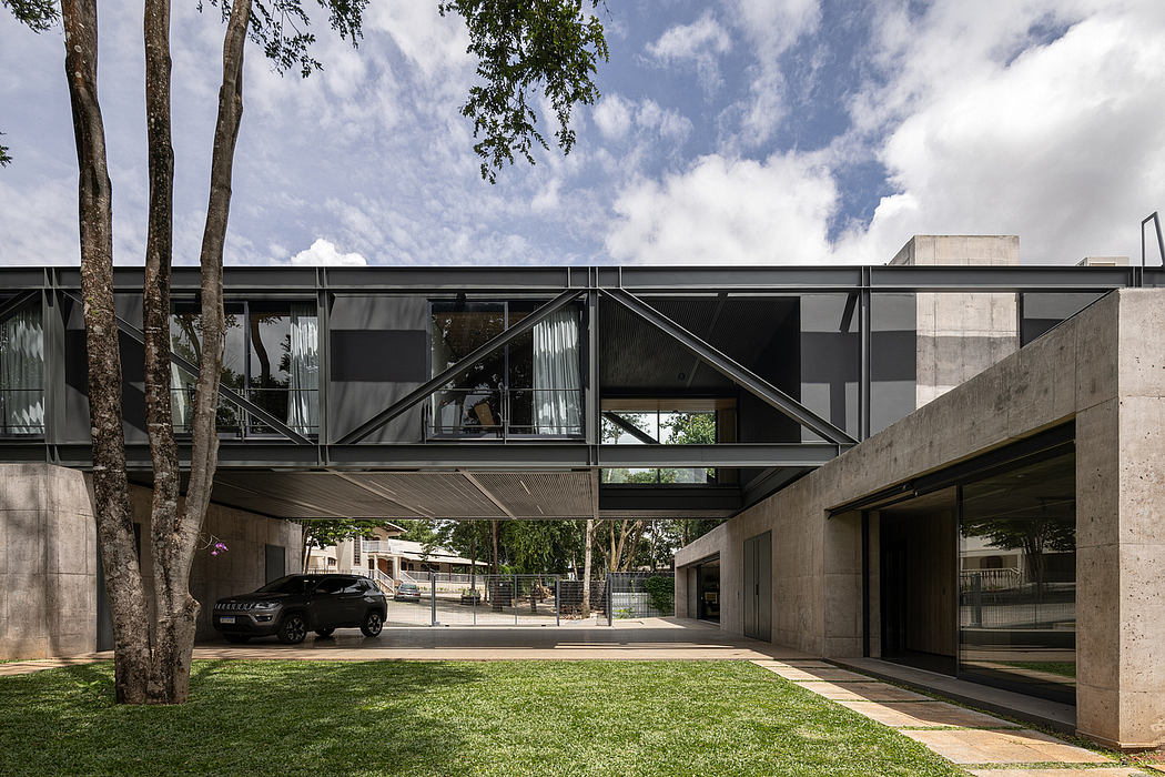 A modern concrete and glass building with a triangular roofline and lush greenery.