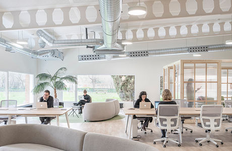 Modern and airy co-working space with exposed ductwork, natural light, and minimalist furniture.