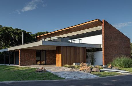 A modern, single-story building with a sloped roof, brick walls, and a wooden entrance.