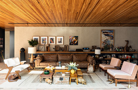 Warm, rustic living room with wooden ceiling, concrete walls, and eclectic furnishings.