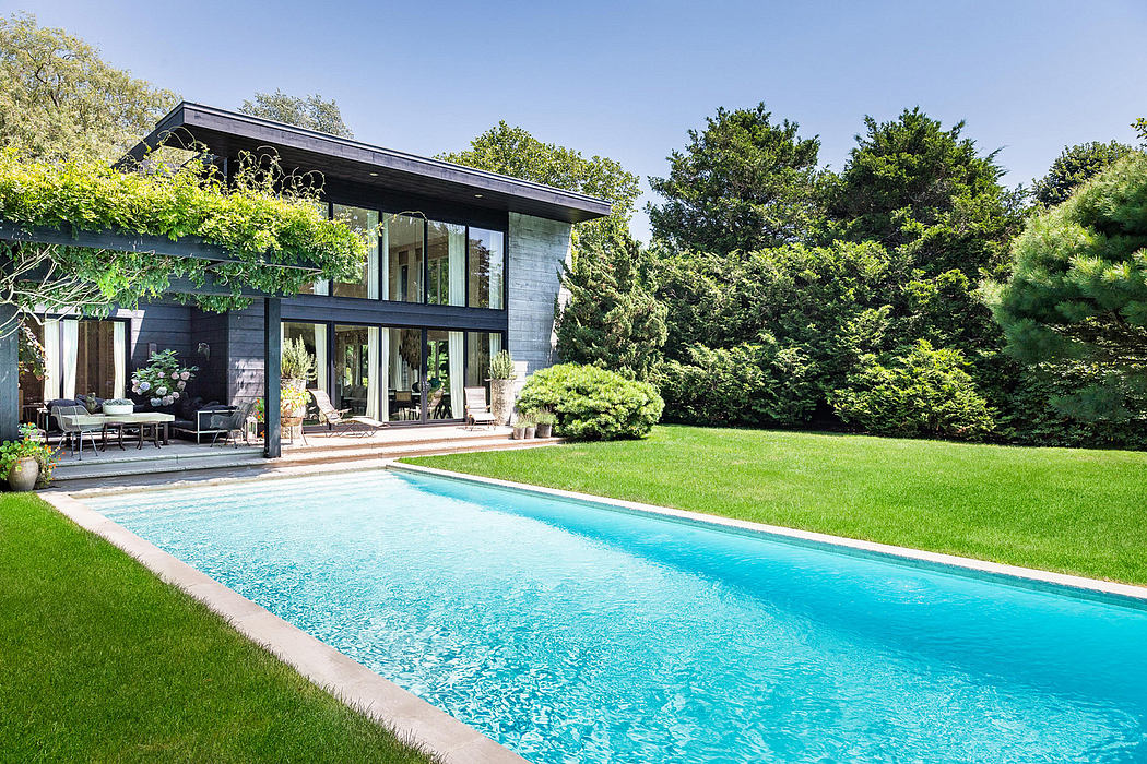 Modern, glass-walled home with sleek design, surrounded by lush greenery and a tranquil pool.