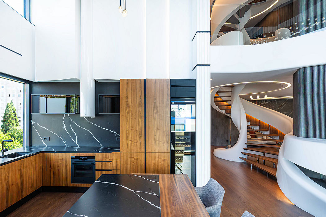 Sleek, modern kitchen with striking marble countertops and wood cabinetry; a spiral staircase leads to an upper level.