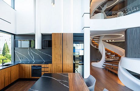 Sleek, modern kitchen with striking marble countertops and wood cabinetry; a spiral staircase leads to an upper level.