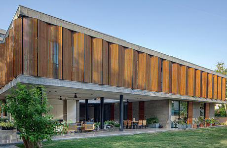 Expansive wooden facade, covered outdoor seating, and natural landscaping elements.