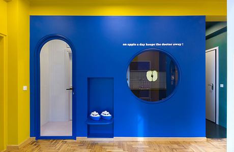 An interior with vibrant blue and yellow walls, circular mirrors, and textured wood flooring.