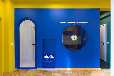 An interior with vibrant blue and yellow walls, circular mirrors, and textured wood flooring.