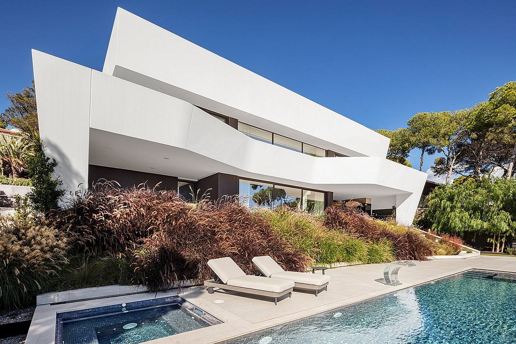 A modern, asymmetrical home with clean lines, a pool, and lush landscaping.