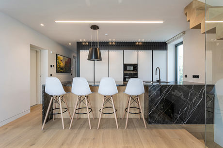 Modern kitchen with sleek black and white cabinetry, marble island, and Eames-style barstools.
