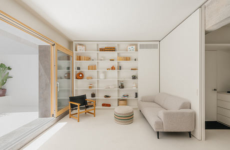 Minimalist living room with built-in shelving, comfortable couch, and wooden accent chair.