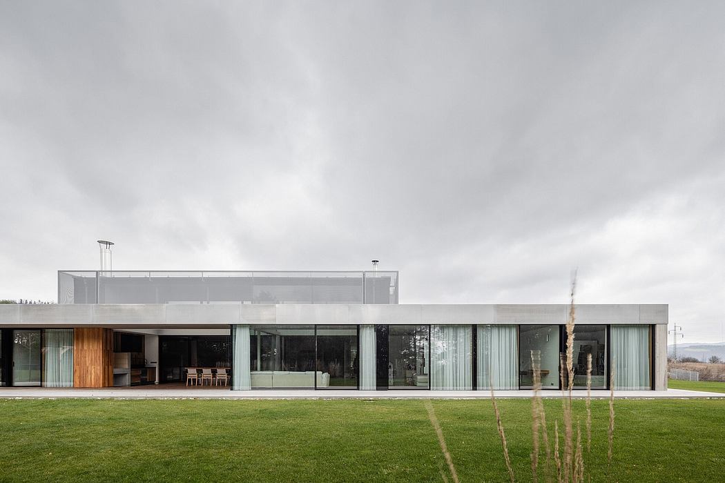 A sleek, modern building with large glass windows overlooking a lush green lawn.