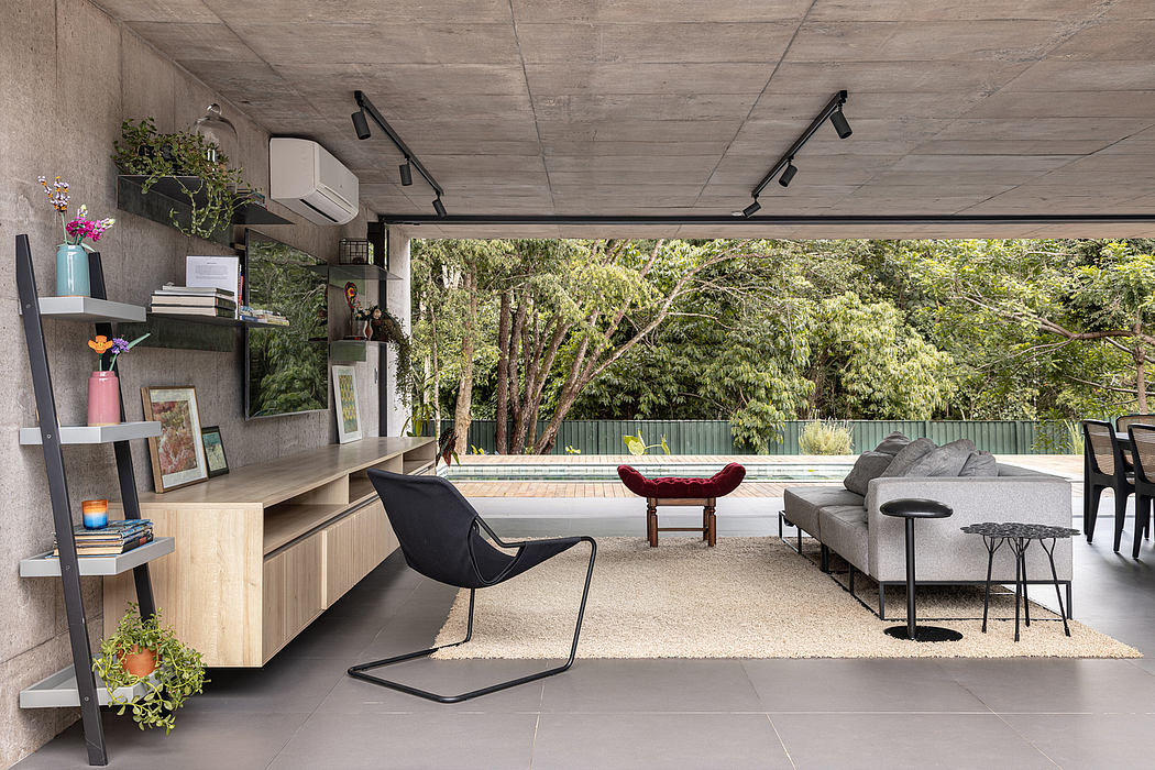 Minimalist concrete interior with modern furniture, floor-to-ceiling windows, and lush greenery.