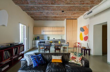 Vibrant open-concept space with exposed brick ceiling, modern kitchen, and eclectic decor.