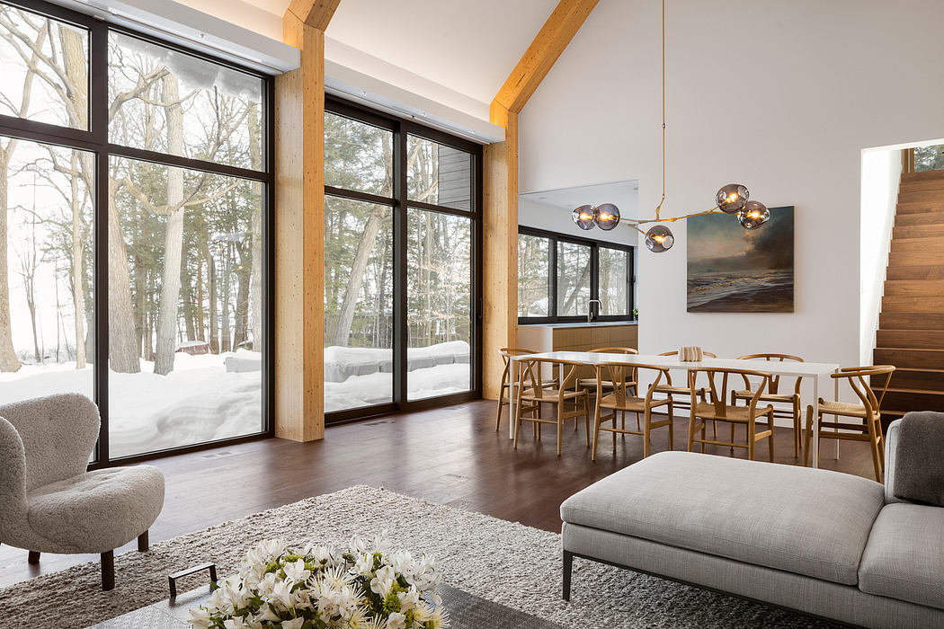 A cozy, modern cabin interior with large windows overlooking a snowy forest scene, featuring wood beams, contemporary furnishings, and a warm, inviting atmosphere.