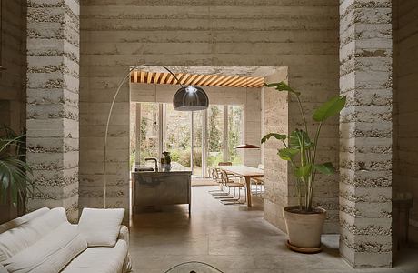 Rustic modern living space with arched entryway, wood-paneled ceiling, and lush greenery.