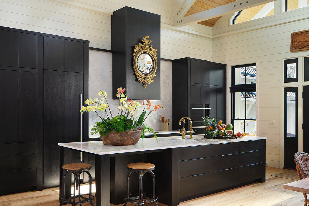 Modern kitchen with black cabinetry, marble countertop, and brass accents; vaulted ceiling with wood beams.