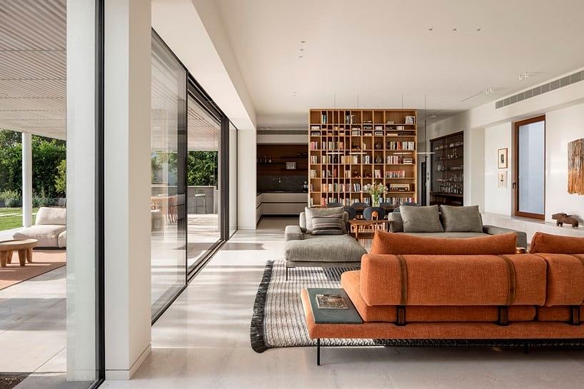 Spacious open-plan living area with large windows, built-in bookshelves, and plush sofas.