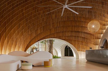 Warm-toned arched ceiling with a central fan, white furniture, and tree in the background.