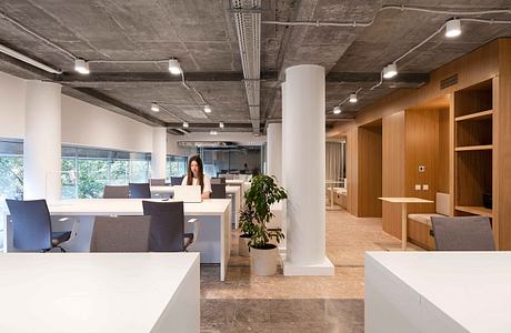 Spacious modern office with concrete ceiling, wooden accents, and workstations.