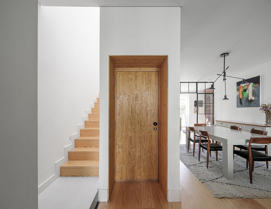 A modern entryway with a wooden door leading into a dining area with a table and chairs.