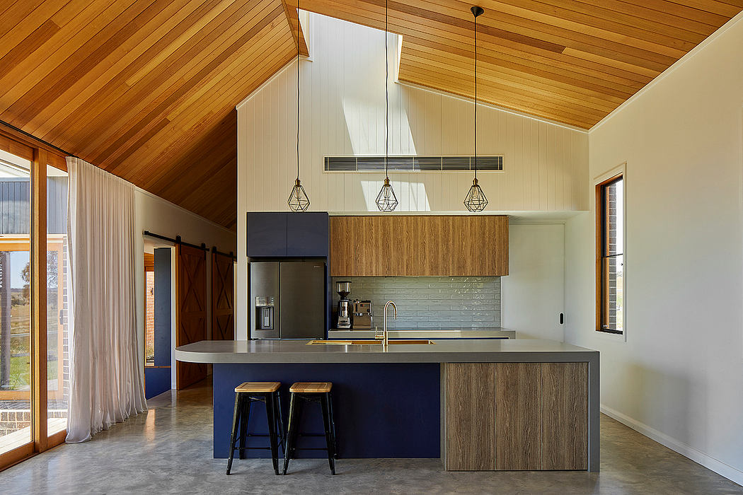 A modern open-concept kitchen with wooden panels, pendant lights, and a sleek island.
