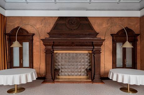 Ornate wood-paneled fireplace with decorative columns and patterned tile surround.
