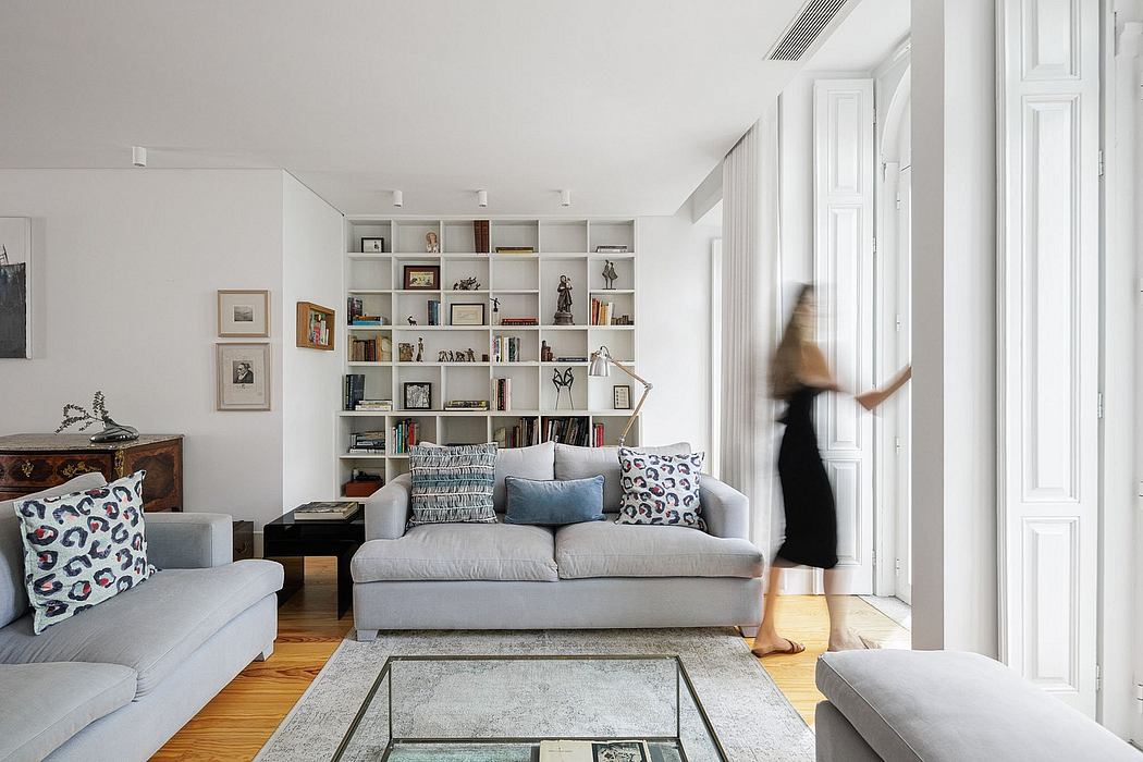 Minimal, modern living room with built-in white bookshelves, plush gray sofas, and wooden floors.