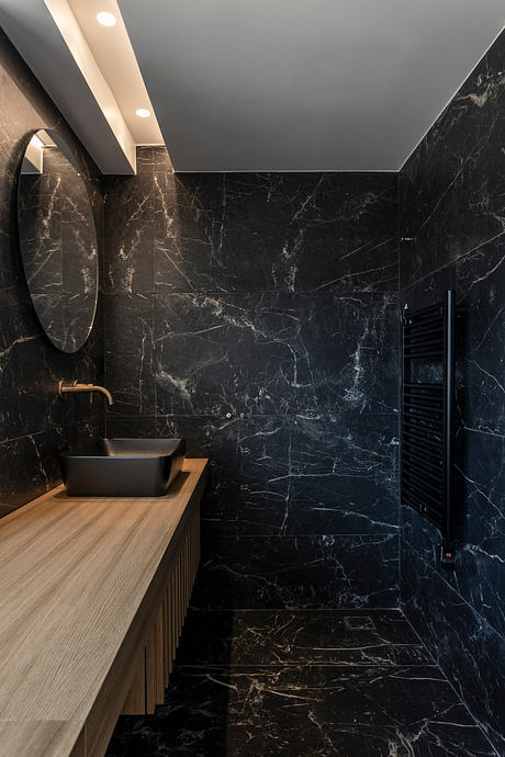 Sleek, contemporary bathroom with black marble walls, minimalist vanity, and recessed lighting.