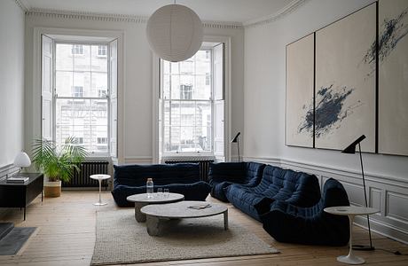 Expansive living room with large windows, ornate moldings, and a striking abstract artwork.