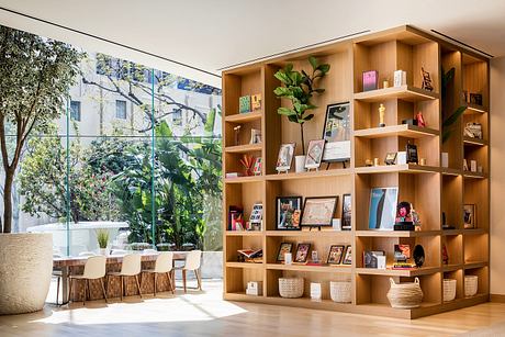 Spacious open-concept interior with wooden shelving, large windows, and lush greenery.