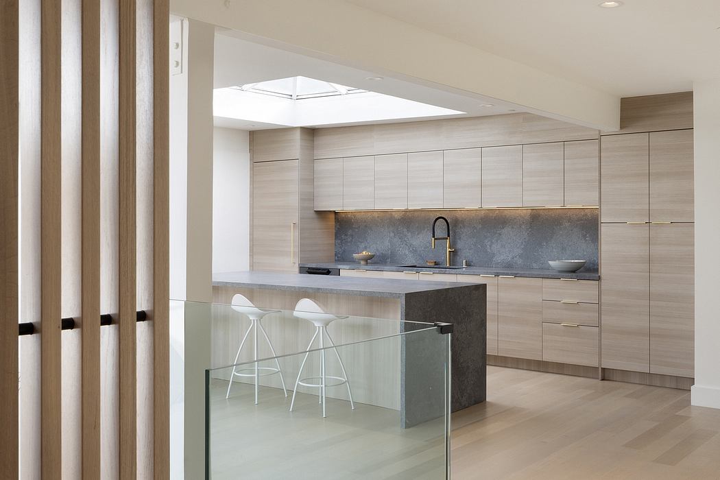 Minimalist kitchen design with wood-paneled cabinets, concrete countertops, and glass divider.