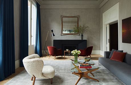 Elegant living room with inviting armchairs, mirrored fireplace, and glass coffee table.