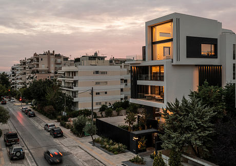 Modern high-rise apartment building with large windows, balconies, and sleek design against cityscape.