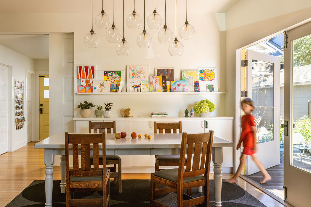Vibrant, modern dining space with colorful artwork, pendant lighting, and a wooden table.