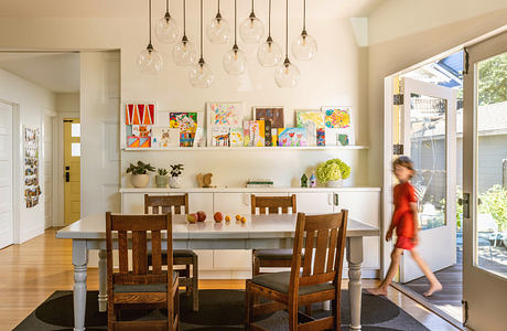 Vibrant, modern dining space with colorful artwork, pendant lighting, and a wooden table.