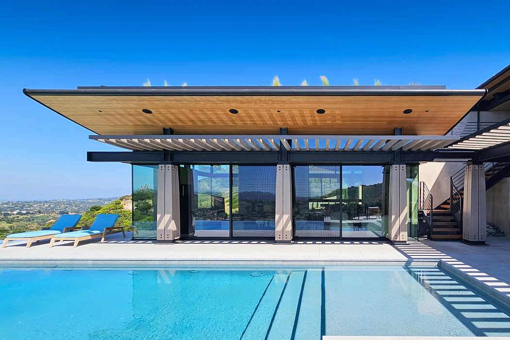 Sleek, modern architecture with wood beams, glass walls, and outdoor pool overlooking hills.