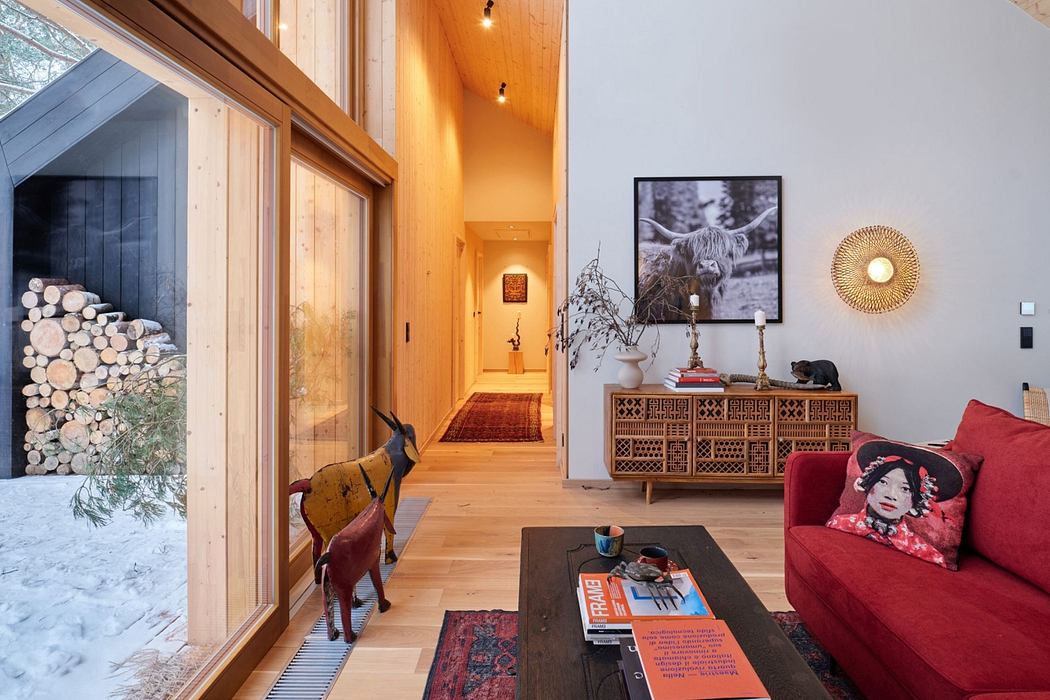 Warm, wooden interior with patterned furniture, artwork, and large windows overlooking snowy landscape.