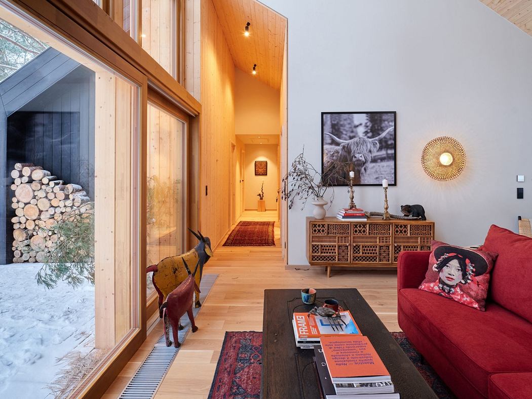 Warm, wooden interior with patterned furniture, artwork, and large windows overlooking snowy landscape.