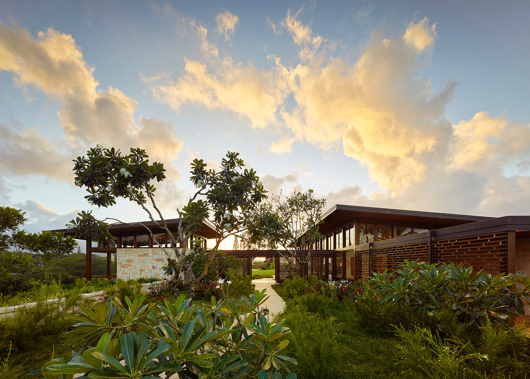 Modern tropical architectural design with lush greenery and vibrant clouds.