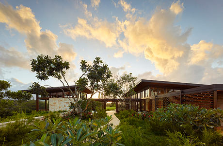 Modern tropical architectural design with lush greenery and vibrant clouds.