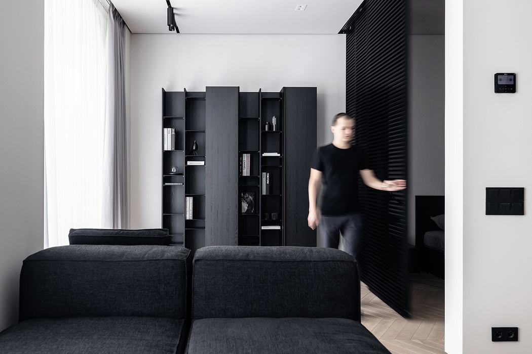 A modern, minimalist living room with sleek black furniture and built-in shelving.