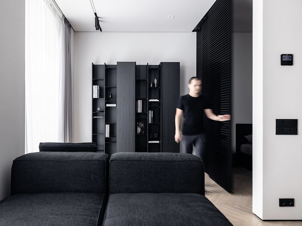 A modern, minimalist living room with sleek black furniture and built-in shelving.