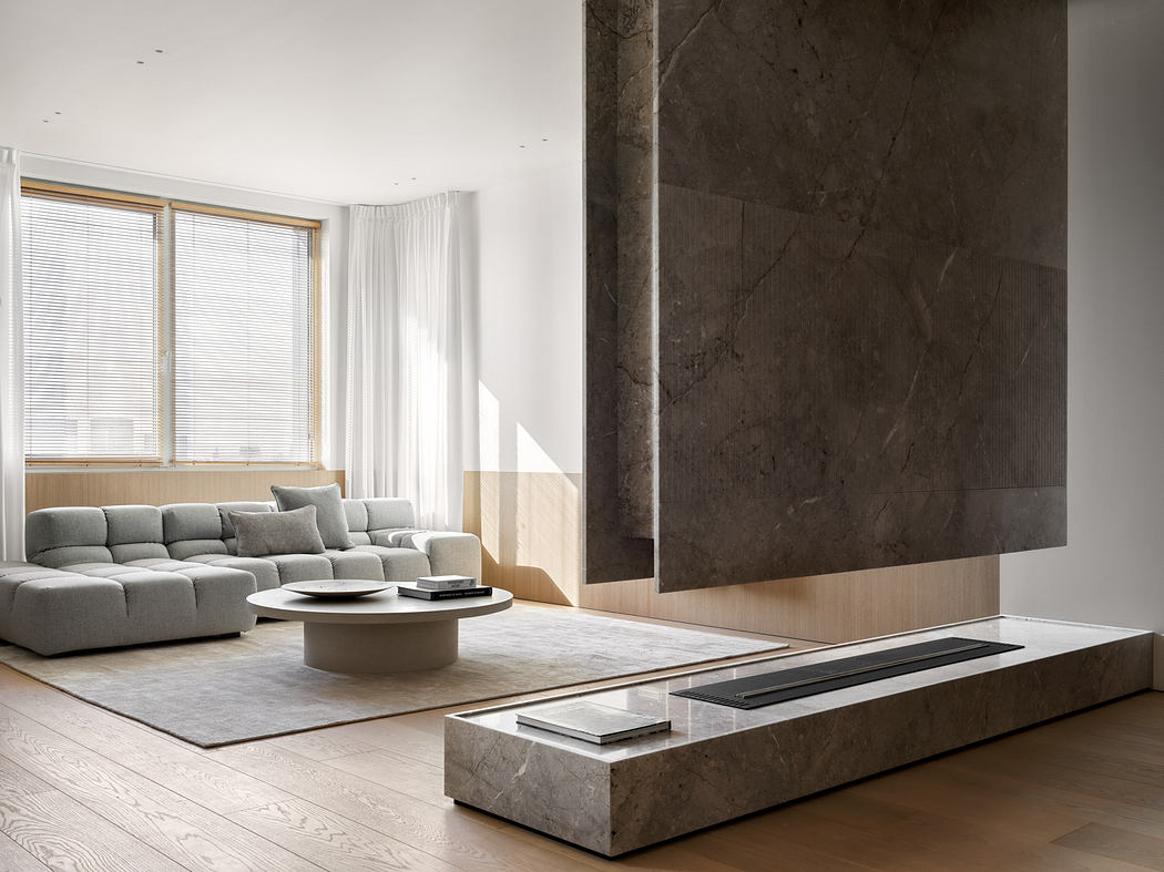 A modern, minimalist living room with a large slate-tiled wall, plush gray sectional, and a low coffee table.