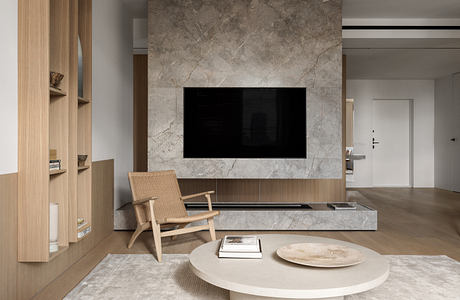 Modern living room with large marble TV wall, minimalist furniture, and natural textures.