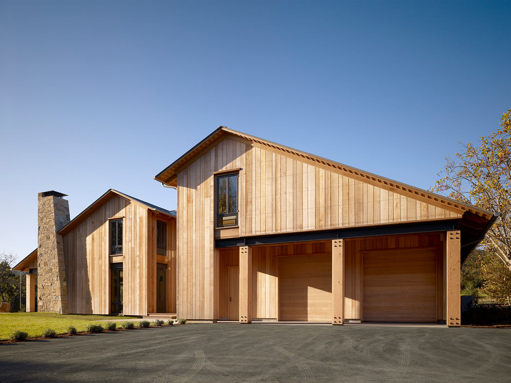 Wooden house with clean, bold lines and large garage doors, set against a clear sky.