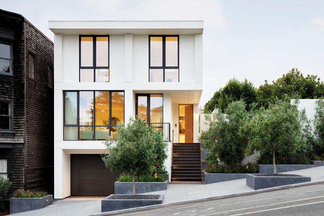 A modern, two-story home with sleek, white exterior, expansive windows, and a welcoming entrance.