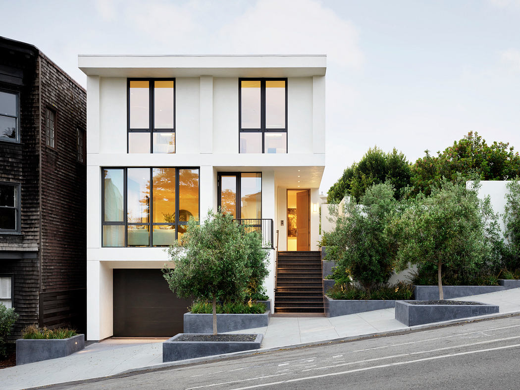 A modern, two-story home with sleek, white exterior, expansive windows, and a welcoming entrance.